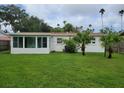 Spacious backyard featuring a sunroom, lush lawn, tropical palms, and complete privacy fence at 3919 Harrisburg Ne St, St Petersburg, FL 33703