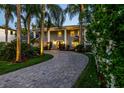 Elegant home with a circular driveway lined with palm trees, complemented by lush landscaping and exterior lighting at 4106 W Cleveland St, Tampa, FL 33609