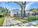 View of home featuring a spacious driveway, updated fence, and a large shade tree at 4516 21St N St, St Petersburg, FL 33714