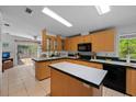 Bright kitchen with an island, tile flooring, wood cabinets, and modern black appliances at 7537 Old Pasco Rd, Wesley Chapel, FL 33544