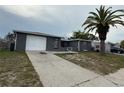 Cozy single-story home featuring a driveway, one-car garage, and a mature palm tree in the front yard at 9815 Wayside Ln, Port Richey, FL 34668