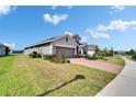 Exterior shot showcasing the home's well-manicured lawn, brick driveway, and landscaping at 11773 Little River Way, Parrish, FL 34219