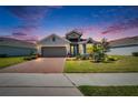 Beautiful exterior view of home at dusk, with a brick driveway, manicured lawn, and lovely landscape lighting at 11773 Little River Way, Parrish, FL 34219