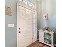 Bright foyer with decorative cabinet, light blue walls, white trim, and a front door with glass panels at 2018 E Del Webb Blvd, Sun City Center, FL 33573