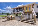 Outdoor living space with a dining area, stairs to the screened porch, and a sunny yellow door at 202 7Th Sw St, Ruskin, FL 33570