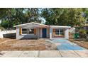Charming single-story home with blue door and light-grey paint on a sunny day at 3020 E Louisiana Ave, Tampa, FL 33610