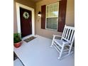 Inviting front porch with a rocking chair, a front door with a wreath, and large window at 5221 Bannister Park Ln, Lithia, FL 33547