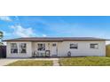 Single-story home featuring a tidy front lawn, welcoming porch chairs, and modern windows at 8240 Jacaranda Ave, Seminole, FL 33777