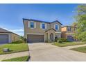 Two-story home boasts a spacious driveway, neutral tones, and well-maintained landscaping at 11476 Sage Canyon Dr, Riverview, FL 33578