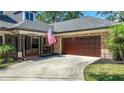 Attached two-car garage and front porch showing architectural details, American flag, and mature landscaping at 213 Sheffield E Cir, Palm Harbor, FL 34683