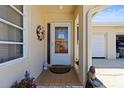 Close-up of front door with decorative wreath, welcome mat, sidelight window and potted plants at 2735 Sherbrooke Ln # D, Palm Harbor, FL 34684