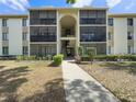 Well-maintained condo building with screened balconies and landscaped grounds under a sunny sky at 3188 Lake Pine S Way # B1, Tarpon Springs, FL 34688