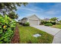Single-level home featuring a two-car garage, green lawn, and privacy hedges at 3726 Rain Tree Ct, Palm Harbor, FL 34685