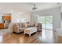Open-concept living room features wood floors, neutral decor, and sliding door access to the pool area at 5526 Braddock Dr, Zephyrhills, FL 33541