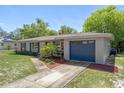 Charming home showcasing a well-kept lawn, mature landscaping, and a single-car garage, complemented by blue shutters at 6268 Harcross Ct, Spring Hill, FL 34606