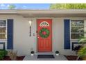 Close-up view of a vibrant red front door with decorative wreath, enhancing curb appeal with modern accents at 6268 Harcross Ct, Spring Hill, FL 34606