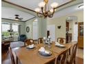 Formal dining room with wood table set for six, chandelier, and view of living area at 8202 Pinewood Run Ct, Tampa, FL 33647