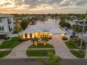 Aerial view of a well-manicured home with a circular driveway, lush landscaping, and water views at 935 Eden Isle Ne Dr, St Petersburg, FL 33704