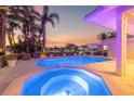 Beautiful backyard featuring a large swimming pool, spa, covered patio, and lush tropical landscaping overlooking the water at 935 Eden Isle Ne Dr, St Petersburg, FL 33704