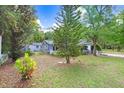 A view of the backyard that shows a large grassy area and mature trees offering lots of shade at 10130 Burton St, New Port Richey, FL 34654