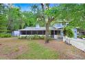 Expansive front yard showcasing mature trees, a screened porch, and a classic picket fence at 10130 Burton St, New Port Richey, FL 34654