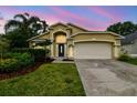 Charming single-Gathering home featuring a manicured lawn and attached two-car garage at sunset at 10223 Charleston Corner Rd, Tampa, FL 33635
