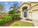 Eye-catching home featuring lush landscaping surrounding the blue door and two-car garage at 10223 Charleston Corner Rd, Tampa, FL 33635