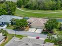 An aerial view displays this home with a large driveway, mature trees, and a nearby water feature and golf course at 10324 Chatuge Dr, San Antonio, FL 33576