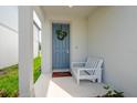 Welcoming front porch features a blue door, wreath, a white bench, and a welcome mat at 20472 Monza Loop, Land O Lakes, FL 34638
