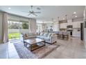 Open-concept living room with a large sectional sofa, kitchen island, and sliding glass doors to backyard at 20472 Monza Loop, Land O Lakes, FL 34638