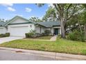 Charming home with a well-manicured lawn, mature landscaping, and an attached garage at 235 Woodridge Cir, Oldsmar, FL 34677