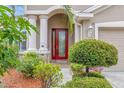 Inviting front entrance with a red glass door, flanked by columns and lush greenery at 3510 Hickory Hammock Loop, Wesley Chapel, FL 33544