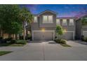 Twilight view of the townhouse with an attached two-car garage and well-maintained landscaping at 5922 Grand Sonata Ave, Lutz, FL 33558