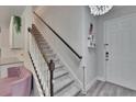 Bright foyer featuring a staircase, modern lighting, and a glimpse of the adjacent living space at 5922 Grand Sonata Ave, Lutz, FL 33558