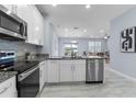Modern kitchen featuring stainless steel appliances, granite countertops, and white cabinetry at 8605 N Taliaferro Ave, Tampa, FL 33604