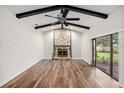 Inviting living room featuring a stone fireplace, wooden floors, a vaulted ceiling with beams, and sliding glass doors to outside at 14 Idlewilde Dr, Safety Harbor, FL 34695