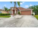 Inviting single-story home featuring a landscaped front yard, arched windows, and a two-car garage at 18005 Palm Breeze Dr, Tampa, FL 33647