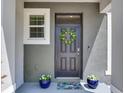 Close up of the front door featuring a beautiful wreath, potted plants, and a welcome mat at 2882 Suncoast Plains Dr, Odessa, FL 33556