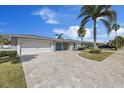 Beautifully landscaped home with a brick driveway, mature trees, and a charming light blue entrance at 3910 Doral Dr, Tampa, FL 33634