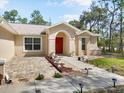 Charming front entrance featuring a red door, manicured landscaping, and a welcoming walkway with lights at 10423 Sand Lark Ave, Weeki Wachee, FL 34614