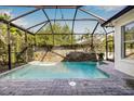 Screened-in pool area featuring a stone waterfall and lush landscaping at 11611 Meridian Point Dr, Tampa, FL 33626