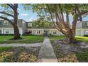 Inviting condo exterior with mature trees and landscaped yard, creating a peaceful setting at 1705 Belleair Forest Dr # B, Belleair, FL 33756