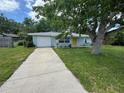 The exterior features a blue house with a yellow front door, a driveway, and mature trees at 1713 Valencia E Dr, Largo, FL 33778