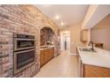 A bright kitchen with stainless steel appliances, tile floors, and a brick archway at 6711 Thackston Dr, Riverview, FL 33578