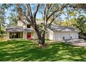Two-story home with a three-car garage, screened porch, mature trees, and manicured lawn at 1800 Salem Ct, Dunedin, FL 34698
