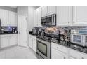 Modern kitchen with white cabinets, stainless steel appliances, black countertops, and a stylish tile backsplash at 3009 Banyan Hill Ln, Land O Lakes, FL 34639