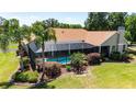 Backyard oasis featuring a screened-in pool area surrounded by beautiful landscaping and mature trees at 30723 Reed Rd, Dade City, FL 33523