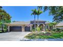 Stunning home exterior featuring a three-car garage, lush landscaping, and decorative palm trees at 3212 Sunset Lakes Blvd, Land O Lakes, FL 34638