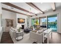 Bright living room featuring exposed beams, waterfront view through sliding glass doors, and comfortable seating at 5142 W San Jose St, Tampa, FL 33629