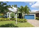 Charming home showcasing mature palm trees, meticulously maintained landscaping, and a brick paver driveway at 6417 Blue Sail Ln, Apollo Beach, FL 33572